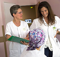 Médecin et infirmière souriantes au chevet d'une patiente atteinte de cancer - Agrandir l'image (fenêtre modale)
