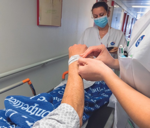 Un soignant attache un bracelet d'identification au bras d'un patient sur un brancard